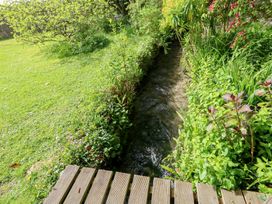 A garden with a stream and wooden decking at Millmead House Portesham