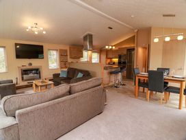 A living room with a sofa, television, and dining area at L21 Coastal Kippford in Kippford near Sandyhills