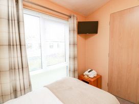 A bedroom with a bed, television, and window at L21 Coastal Kippford in Kippford near Sandyhills