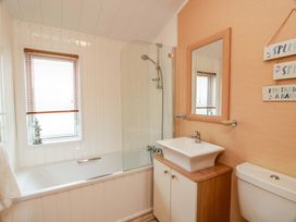 A bathroom with a bathtub, shower, sink, and toilet at L21 Coastal Kippford in Kippford near Sandyhills