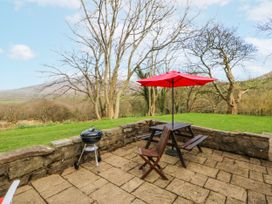An outdoor seating area with a red umbrella and grill at Llwyn Y Brig Isaf in Caernarfon