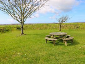 A picnic table under a tree in a garden at Park Hall Cottage in Solva
