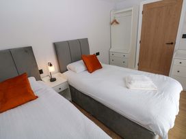 A bedroom with two beds and a wardrobe at Y Bwthyn in Burry Port