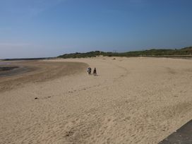 A beach with children walking on the sand at Y Bwthyn Burry Port