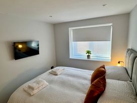 A bedroom with a bed, television, and window at Y Bwthyn in Pembrey