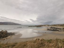 A beach with rocks and houses under a cloudy sky at 2 Ard an Chuain Dunfanaghy