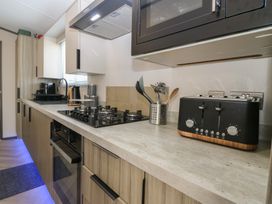 A kitchen with a microwave, toaster, gas stove, and kitchen utensils at Plot 243 - Coldingham Bay Leisure Park Eyemouth