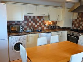 A kitchen with appliances and a dining table at Bracken Lodge in Finlakes Holiday Park near Chudleigh