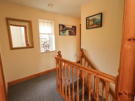 A hallway with a mirror, window, and pictures at 4 Mellbecks Mews Kirkby Stephen