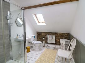 A bathroom with a shower, toilet, sink and a chair at Childwall Cottage TULLOGHER