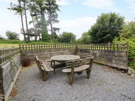 A garden with a wooden table and chairs surrounded by a fence at Childwall Cottage TULLOGHER
