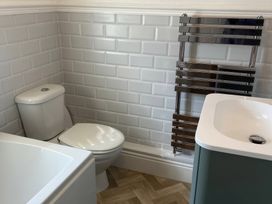 A bathroom with a toilet, bathtub, towel radiator, and sink at 3 Newboro Terrace Conwy