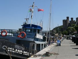 A fishing boat docked at the harbor near a castle at 3 Newboro Terrace in Conwy