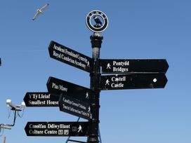 A directional signpost with various locations listed at 3 Newboro Terrace Conwy