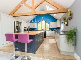 A kitchen with an island and bar stools at Hazeldene near Harvington