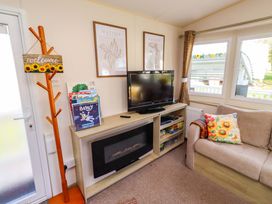 A living room with a sofa and television at Sunflower Retreat, Caravan 61