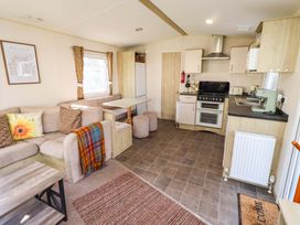 A kitchen area with a sofa and dining table at Sunflower Retreat, Caravan 61