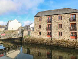 A building by the water with a bridge in front at Apartment 6 in Penryn