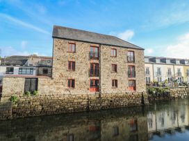 A stone building with windows and balconies near a river at Apartment 6 Penryn
