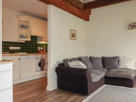 A living room with a sofa and kitchen area at Daniel’s Sail Loft Penthouse in Penryn