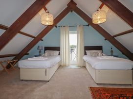 A bedroom with two beds, lamps, and curtains at Daniel’s Sail Loft Penthouse in Penryn