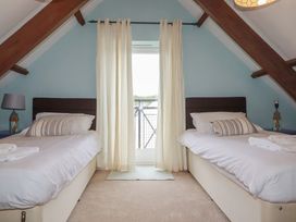 A bedroom with twin beds and a balcony door at Daniel’s Sail Loft Penthouse in Penryn