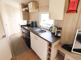 A kitchen with stove and sink at The Seafront Cosy Caravan in Ingoldmells