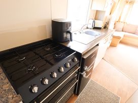 A kitchen with a gas stove, sink, kettle, and fridge at The Seafront Cosy Caravan in Ingoldmells