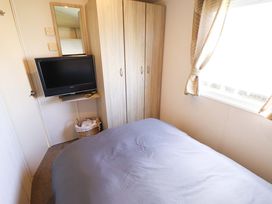 A bedroom with a bed, television, wardrobe, and mirror at The Seafront Cosy Caravan in Ingoldmells
