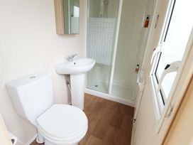 A bathroom with a toilet, sink, and shower at The Seafront Cosy Caravan in Ingoldmells