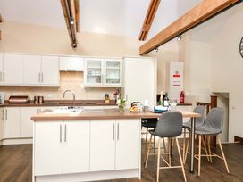 A kitchen with a sink and bar stools at Cider Press Cottage in Torpoint