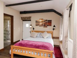 A bedroom with a bed and wall art at Cider Press Cottage in Torpoint