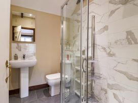 A bathroom with a shower, sink, toilet, and mirror at Cider Press Cottage in Torpoint
