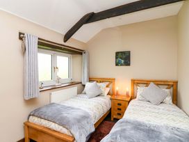 A bedroom with two beds and a window at Cider Press Cottage in Torpoint