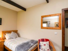 A bedroom with a bed and mirror at Cider Press Cottage in Torpoint