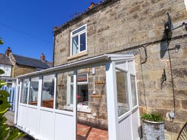 A conservatory with stone walls and windows at Cozy Cottage