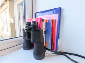 A set of binoculars next to several books on a window sill at Cozy Cottage