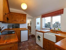 A kitchen with wooden cabinets and appliances at Cozy Cottage in 