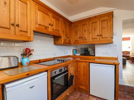 A kitchen with wooden cabinets and appliances at Cozy Cottage