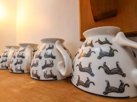 A row of ceramic mugs with cat designs on a shelf at Cozy Cottage
