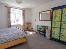 A bedroom with a bed, chair, and wardrobe at Cozy Cottage