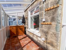 A conservatory with a wooden cabinet and coat hooks at Cozy Cottage