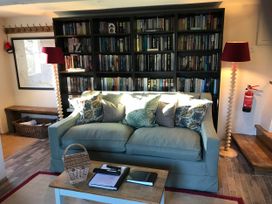 A snug with a sofa, coffee table, bookshelf and a lamp at The Bothy at Lewis Cottage Spreyton