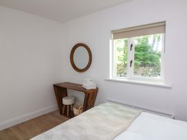 A bedroom with a bed, table, mirror, and window at The Mews @ Derrybawn, Laragh, County Wicklow