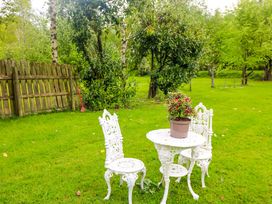 A garden with a table and two chairs beside a flower pot at The Mews @ Derrybawn Laragh, County Wicklow