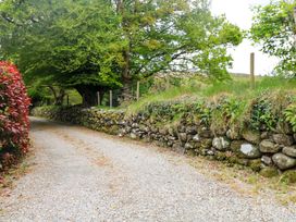 A gravel road bordered by a stone wall and trees at The Mews @ Derrybawn in Laragh, County Wicklow