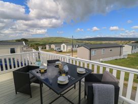 An outdoor patio with a table and chairs overlooking hills at Swanny View in Swanage