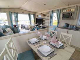A living room with a dining area and kitchen appliances at Swanny View in Swanage