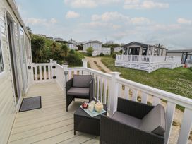 An outdoor area with a deck, chairs, and table at Swanny View in Swanage