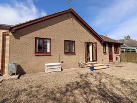 A house with windows and a door leading to a patio area at Willow cottage Seahouses